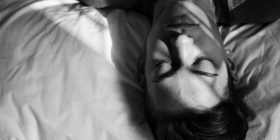 ein schwarz-weiss Bild mit einem jungen Mann, der mit geschlossenen Augen im Bett liegt