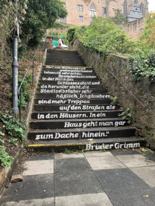 Unterwegs in Marburg. Zu sehen sind beschriftete Treppenstufen mit einem Spruch der Brüder Grimm.