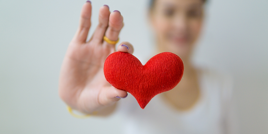 Das Bild zeigt ein DANKE-Herz, das eine junge Frau (verschwommen im Hintergrund) in den Fokus hält. Fotograf: https://www.pexels.com/de-de/foto/gesund-licht-rot-frau-5340267/