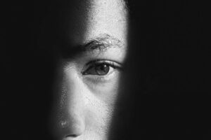 Schwarz-Weiss Foto von Raphael Brasileiro von Pexels (https://www.pexels.com/de-de/foto/schwarz-und-weiss-dunkel-augen-auge-2558823/). Es zeigt ein 
Auge, das aus einem tiefen Schatten Dich direkt anblickt.