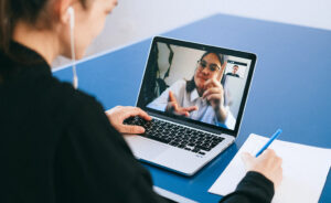Online Konferenz Symbolbild, auf dem ein junges Mädchen auf den Rechner blickt und eine Freundin dort sieht - Foto von Anna Shvets von Pexels